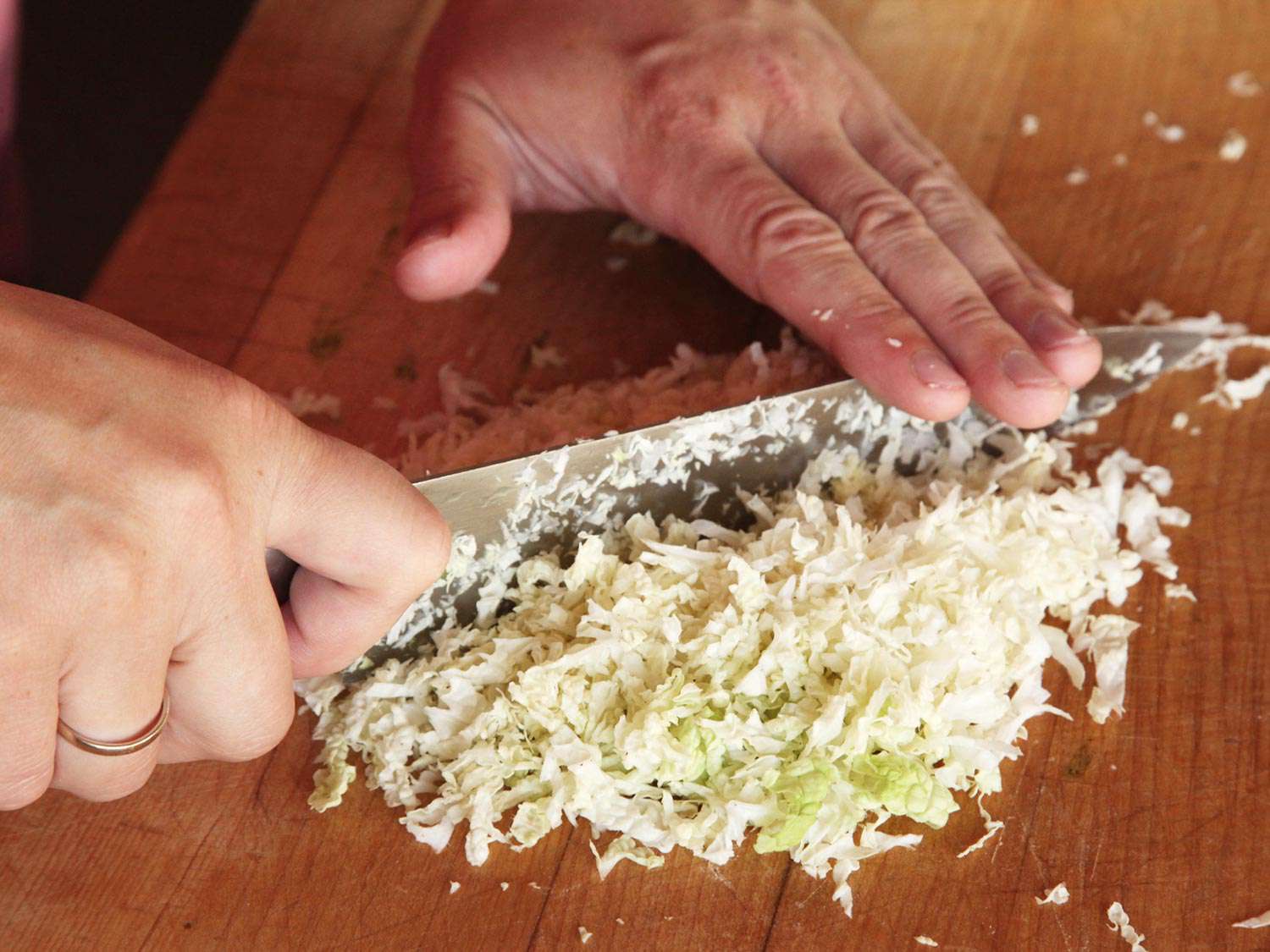 用厨师刀在砧板上切成细丝的纳帕卷心菜。