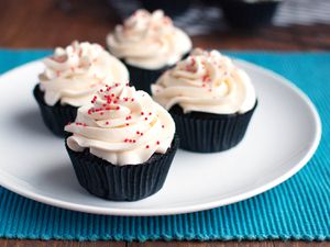 Four buttercream cupcakes resting on a white plate