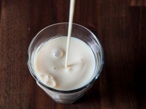 Overhead view of a glass being filled with soy milk.