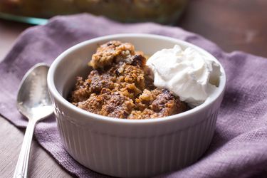 White ramekin filled with apple crisp and whipped cream