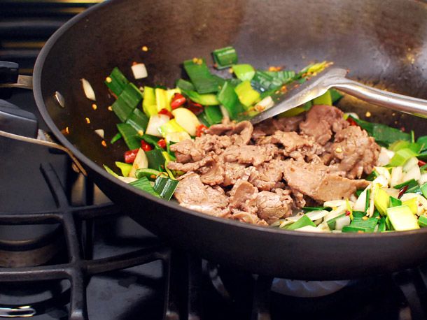 牛肉、韭菜、大蒜和辣椒用金属锅铲在锅里搅拌。
