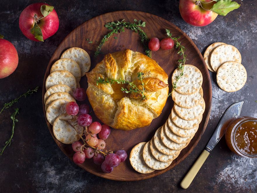 An overhead view of a baked brie adorned with thyme and fig jam.