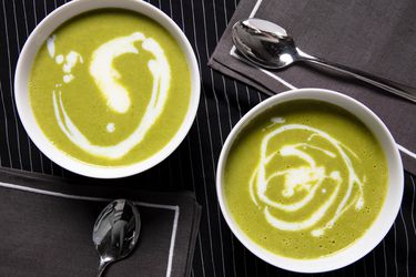 顶视图的卡尔ic scape soup in two white bowls on a black with thin white stripe background and two grey napkins and spoons