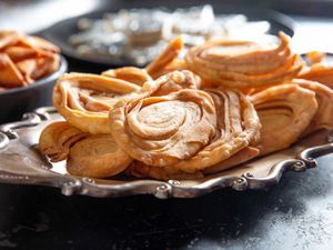 Deep-fried spiralled chiroti on a silver serving platter.