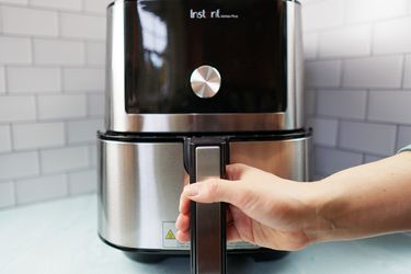 A hand pulling out the basket on an air fryer