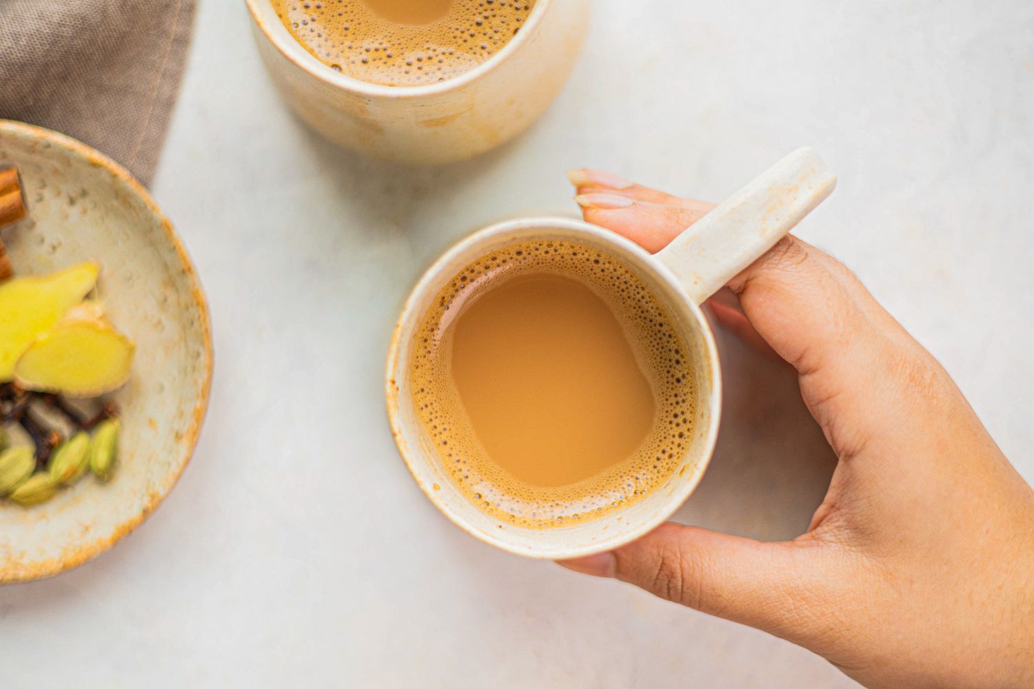 Overhead view of a hand holding a cup of chai