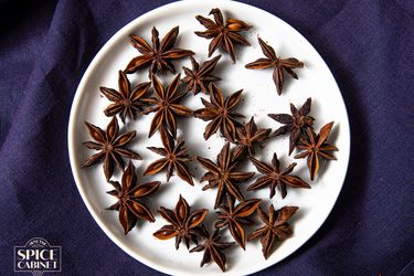 Overhead view of star anise on a plate on a purple background