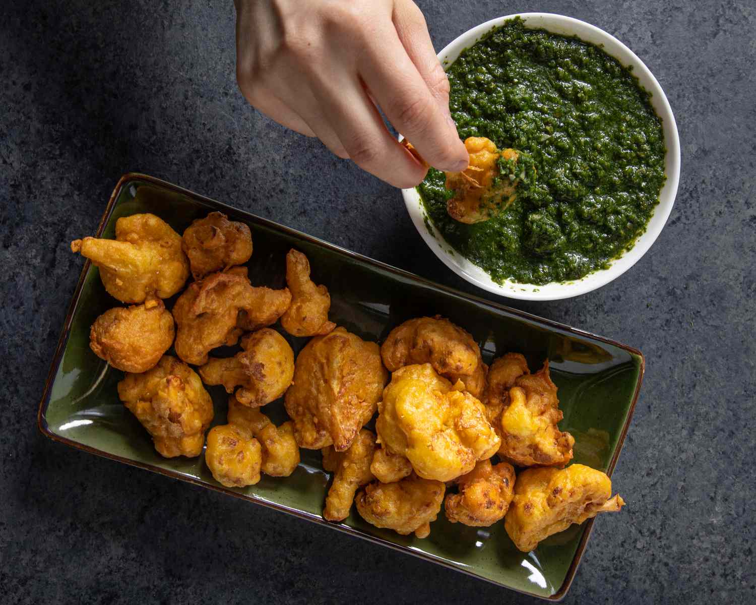 Overhead view of dipping cauliflower Pakora in chutney