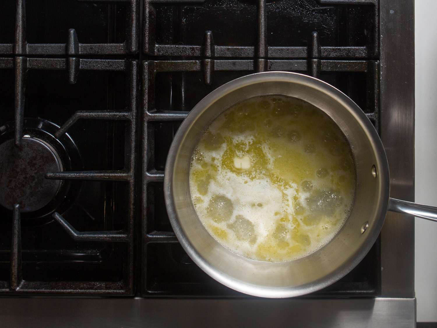Overhead view of the butter and water simmering on a stovetop.