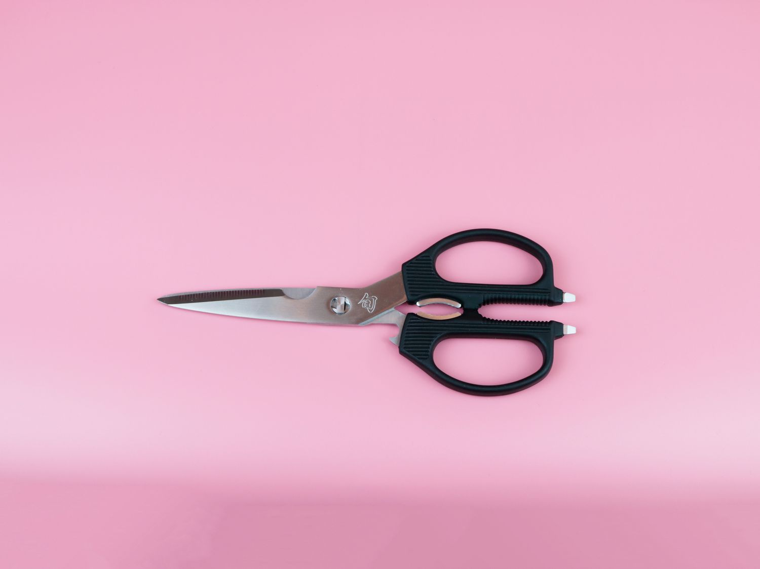 a set of Shun kitchen shears on a pink background