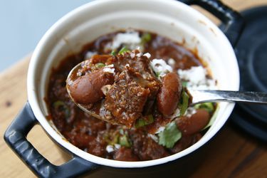 用勺子从小碗里舀出一口牛肉辣椒，露出鲜嫩的豆子和小排骨。