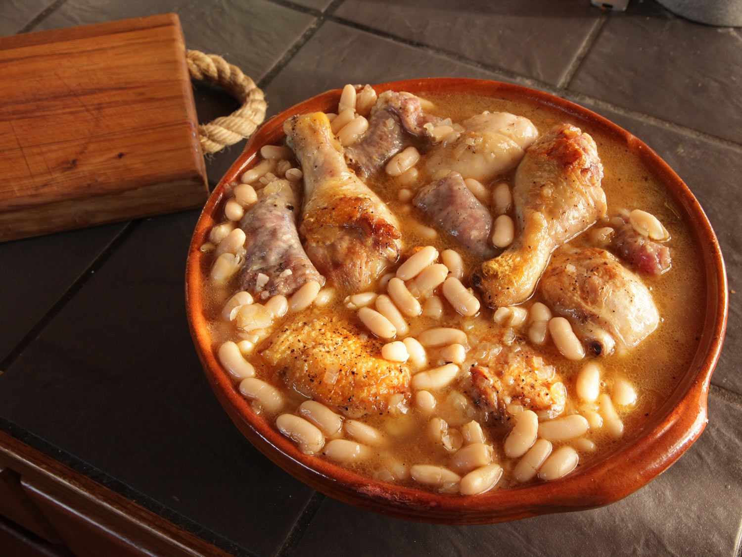 Assembled cassoulet in an earthenware pot before baking.