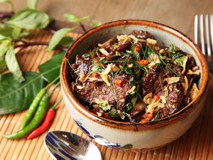 陶制的碗里盛着泰式牛肉，佐以罗勒和辣椒。