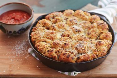 A cast iron pan filled with flavorful pepperoni garlic knots