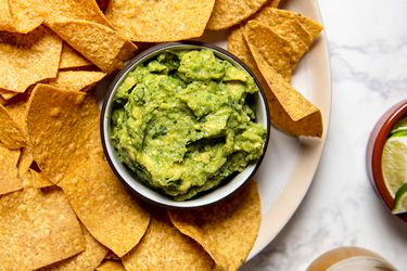 Bowl of guacamole set inside a platter of tortilla chips