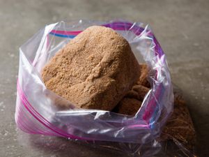 A large, hardened lump of brown sugar in a zip-top bag, the opening of which has been rolled back and propped open.