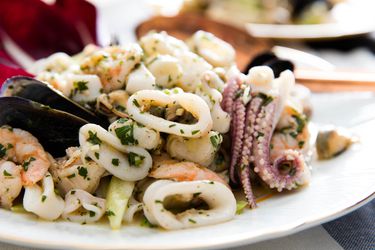 意大利海鲜沙拉鱿鱼,扇贝、萎缩imp, and mussels on a white plate.