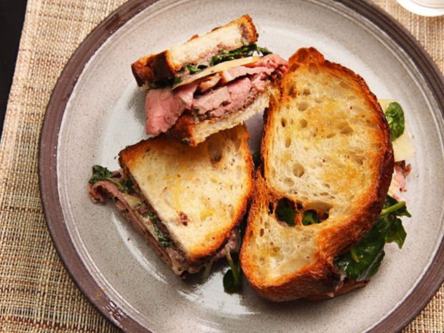 一个完整的羊肉三明治，还有一个切成两半放在盘子里。