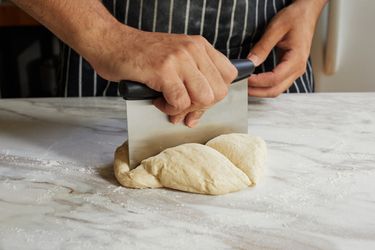 using the oxo bench scraper to cut up pizza dough