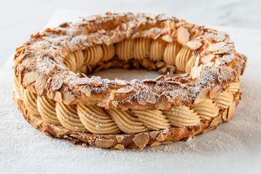 A Paris–Brest (Pâte à Choux With Praline Crème Mousseline) resting on a marble surface