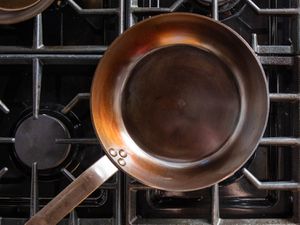 Overhead view of a freshly seasoned carbon steel pan on a gas cooktop.