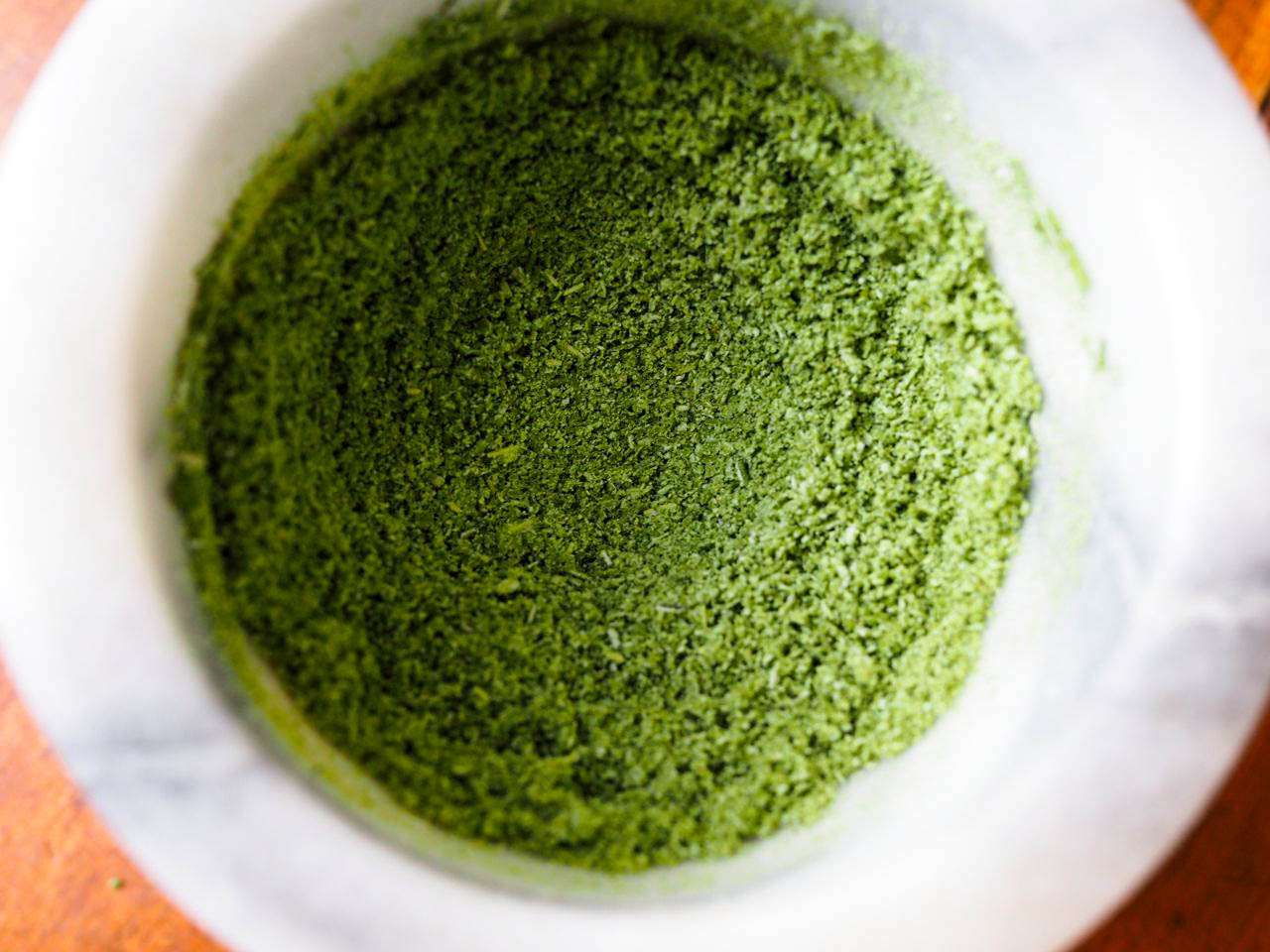 用微波炉烘干的迷迭香叶子，用研钵和杵磨成亮绿色粉末。