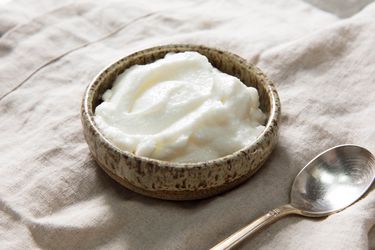 A small bowl of toum, Lebanese garlic sauce, with a spoon next to it.