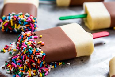 五个自制的布丁棒棒糖放在烤盘上，蘸上巧克力，撒上糖屑。