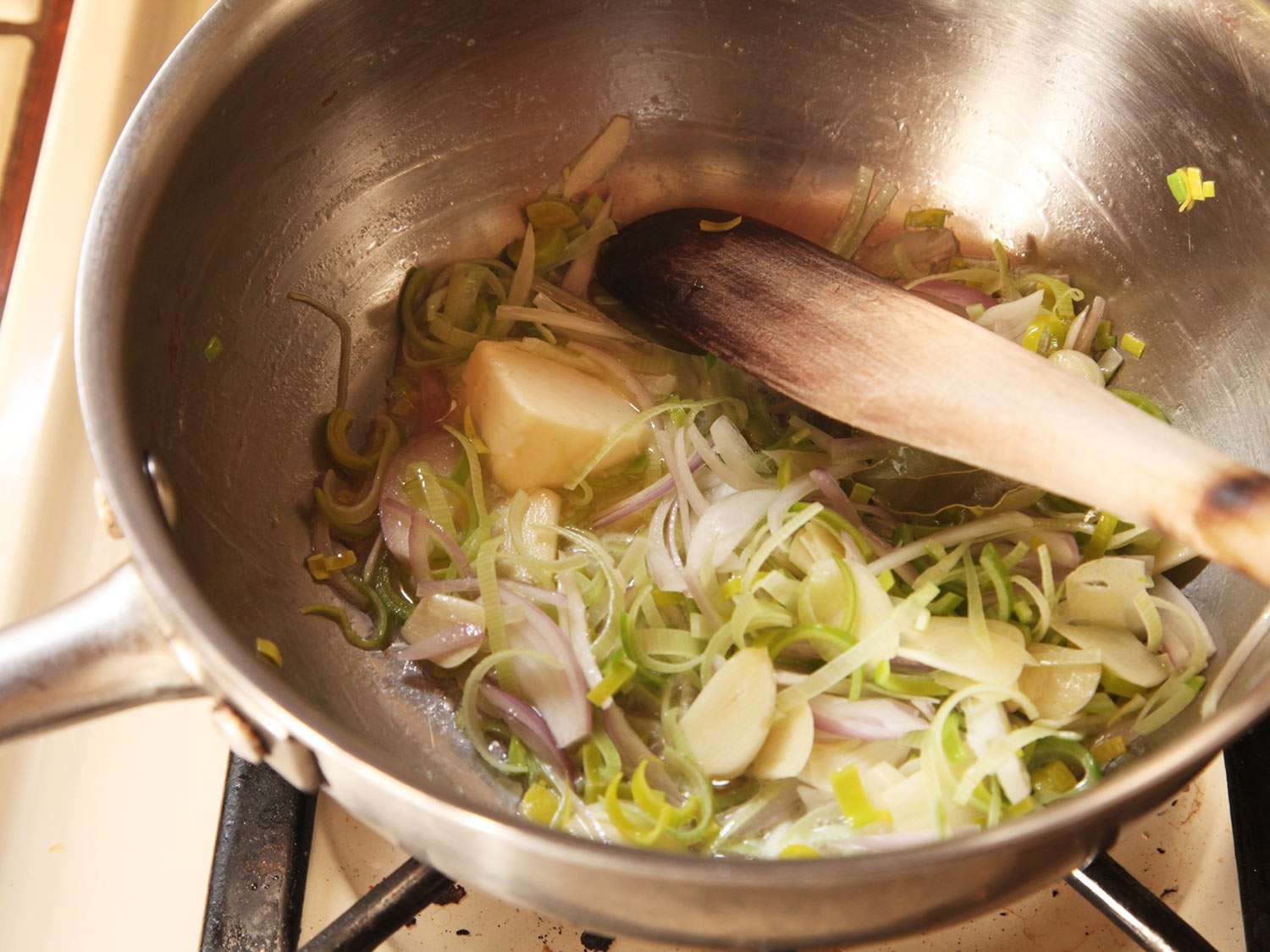 切成薄片的葱、韭菜和大蒜在平底锅中加入黄油。