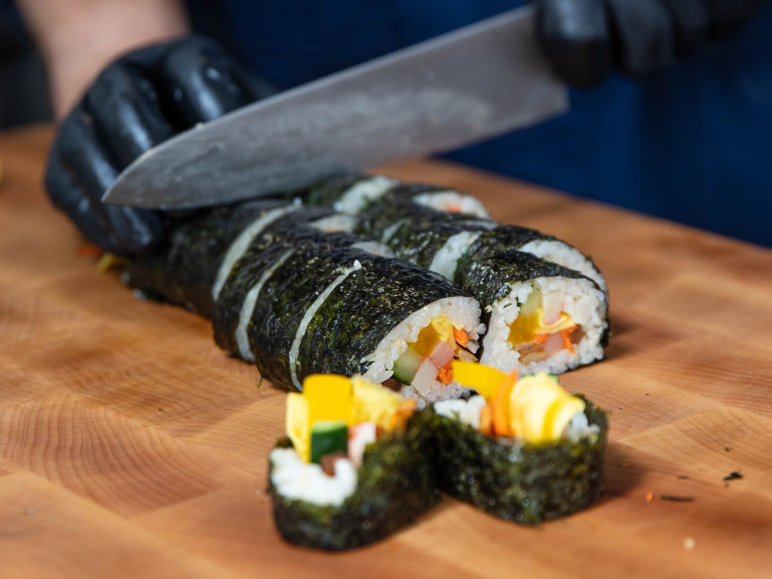 Closeup of a Korean kimbap roll being sliced into rounds.