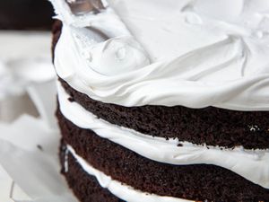 Spreading 7-minute frosting over a chocolate layer cake