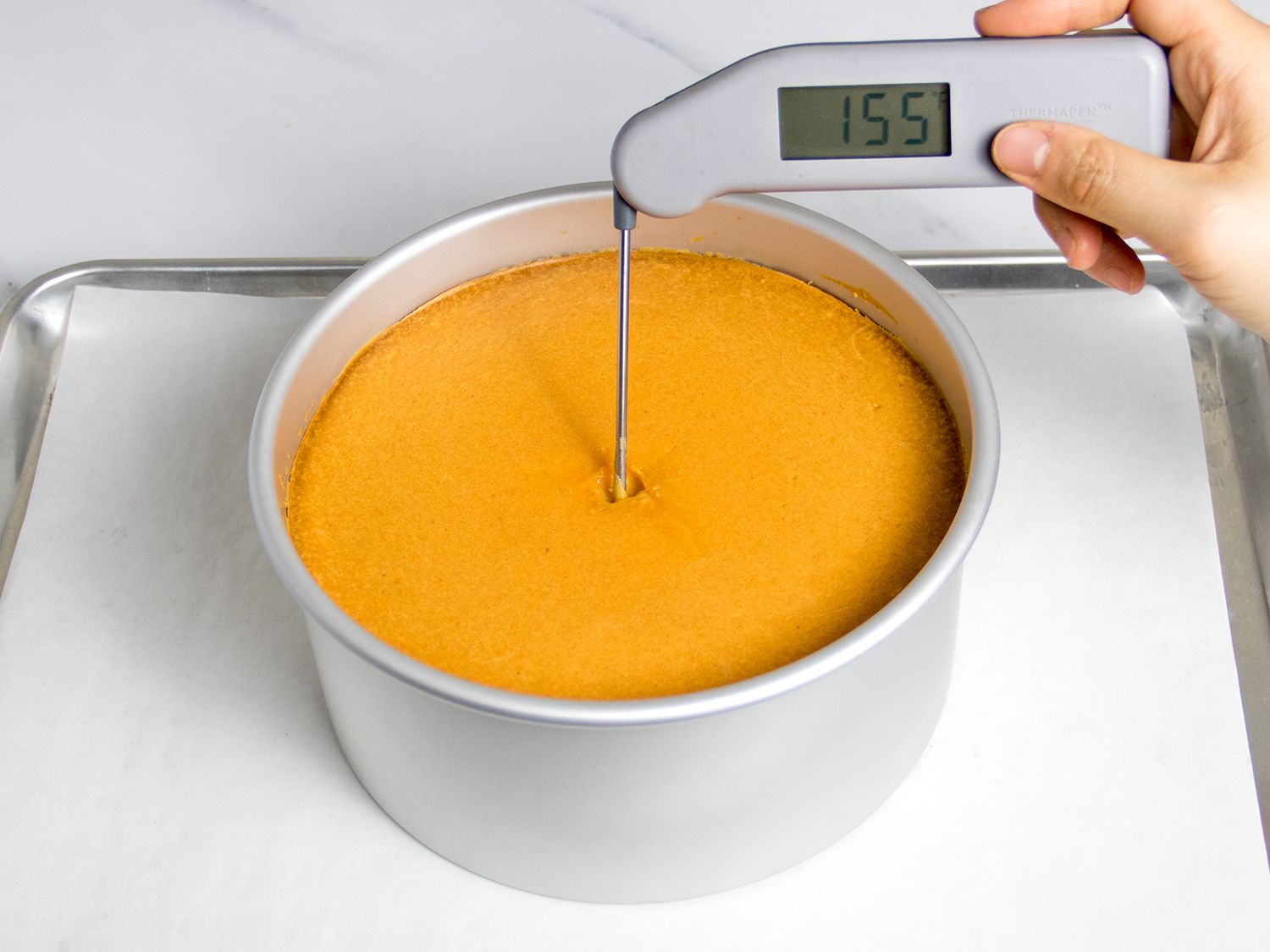 温度计插入烤奶酪蛋糕的中心显示温度为155华氏度。