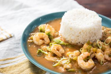 A bowl of shrimp etouffee, with a mound of white rice in the bowl.
