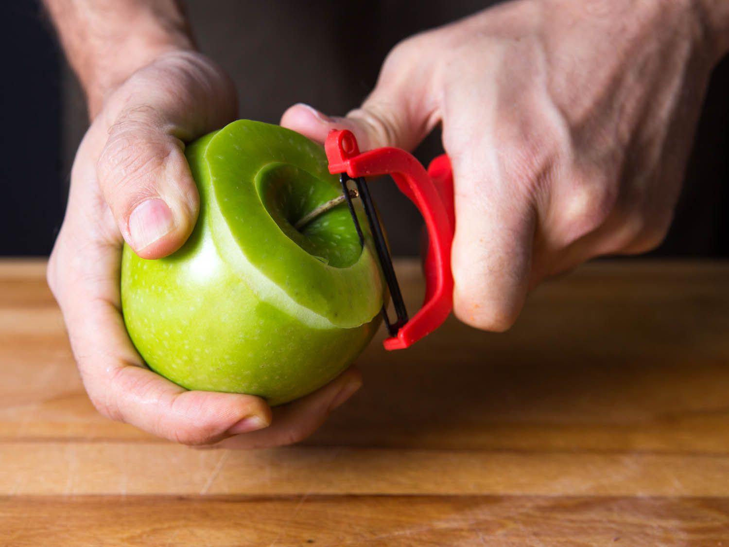 A y-peeler peeling the top of an apple
