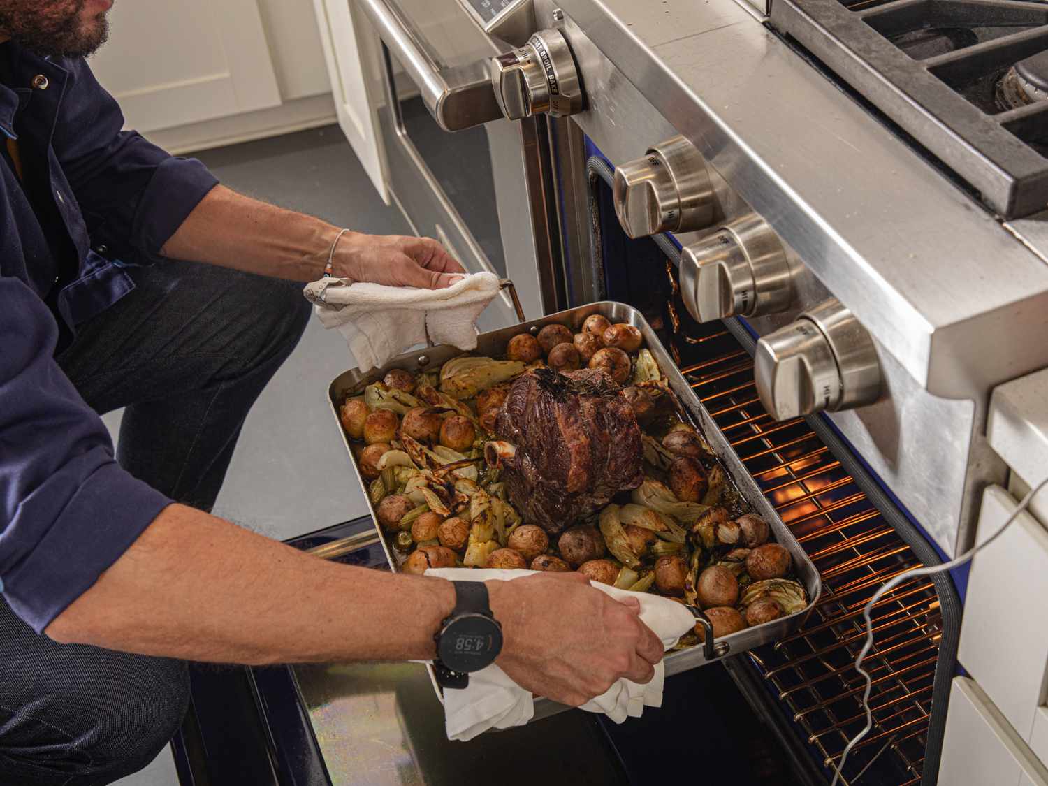 a person putting a full roasting pan into the oven