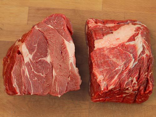 Two large pieces of beef chuck on wooden cutting board