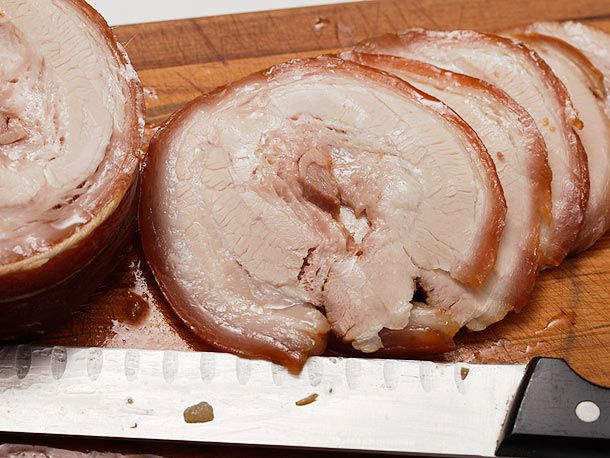 在砧板上用切肉刀切成薄片的叉烧肉。