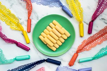 pastillas de leche on a plate surrounded by candy in intricately cut wrappers, an art form known as pabalat