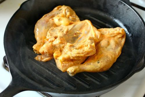一只腌过的、带蝴蝶的、腿上翘的康沃尔母鸡，胸部朝下放在铸铁锅里。