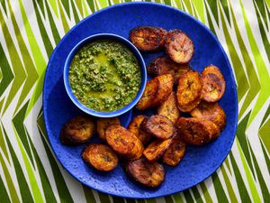 Overhead view of maduros on a blue plate with mint mojos on a striped green background