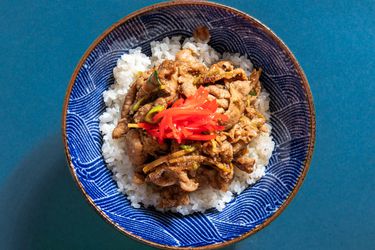 pork ginger over rice garnished with kizami shoga in a blue patterned bowl