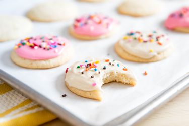 White frosted cookies with sprinkles on a baking sheet