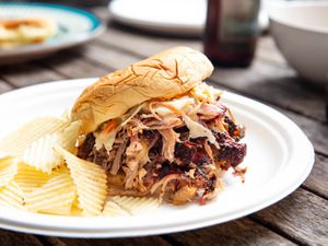 Low-and-slow pulled pork, sandwiched in a bun and served with wavy potato chips.