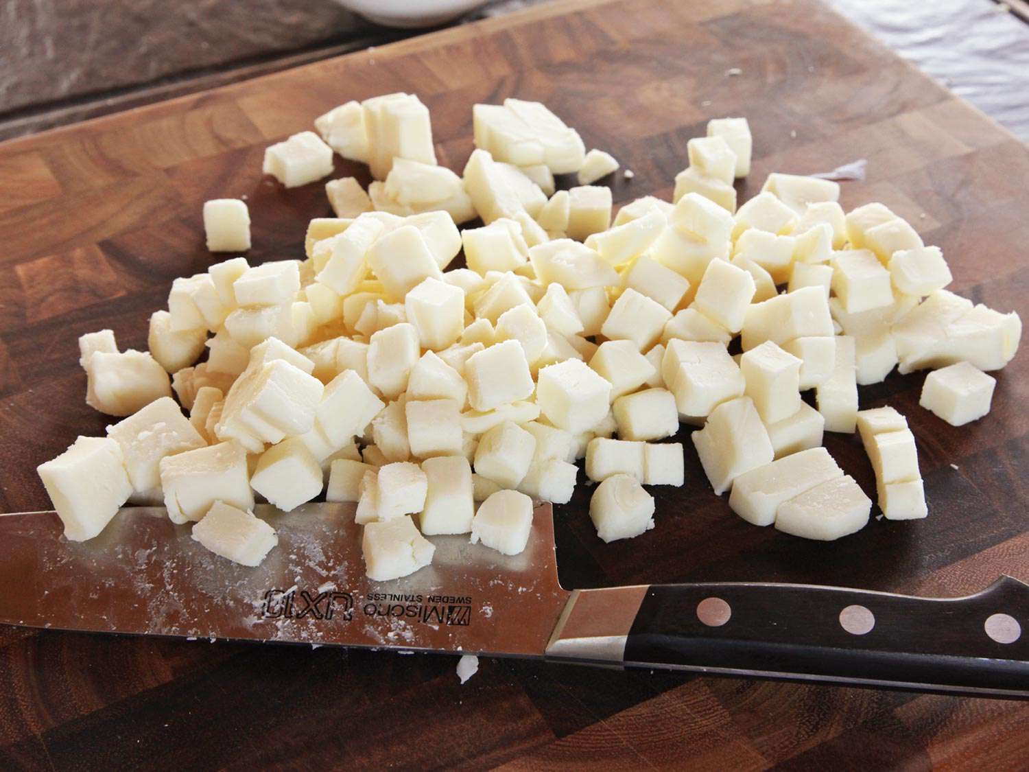 切菜板上放着几块低水分的马苏里拉奶酪，旁边是厨刀。