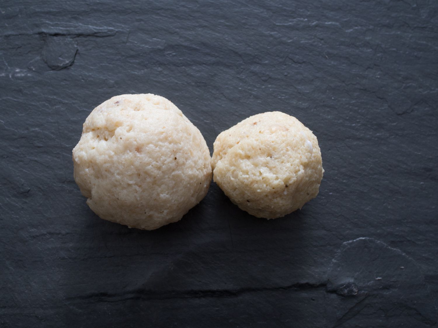 Two matzo balls. The ball on the left has a radius that's nearly half as large as the ball on the right.