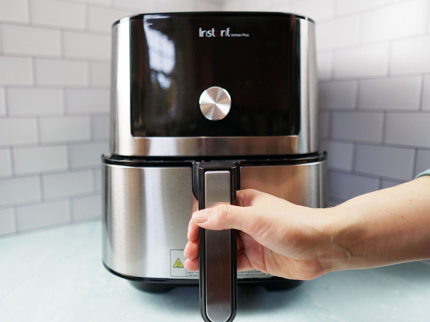 A hand pulling out the basket on an air fryer