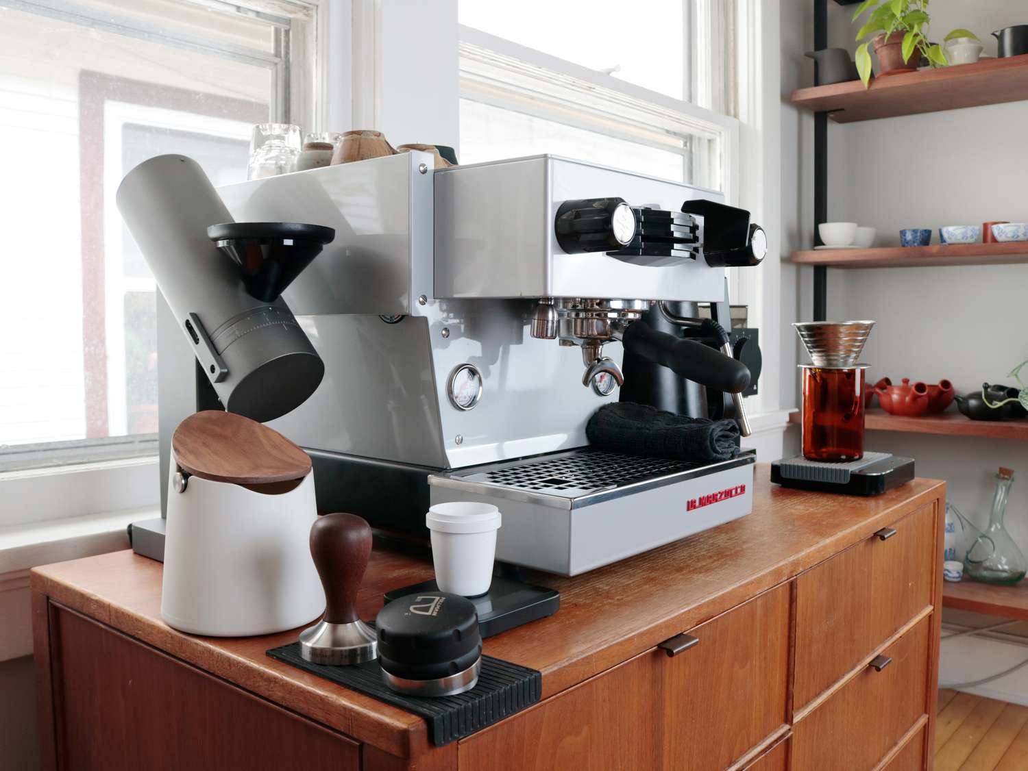 an espresso set up with a knockbox, grinder, tamper, and espresso machine