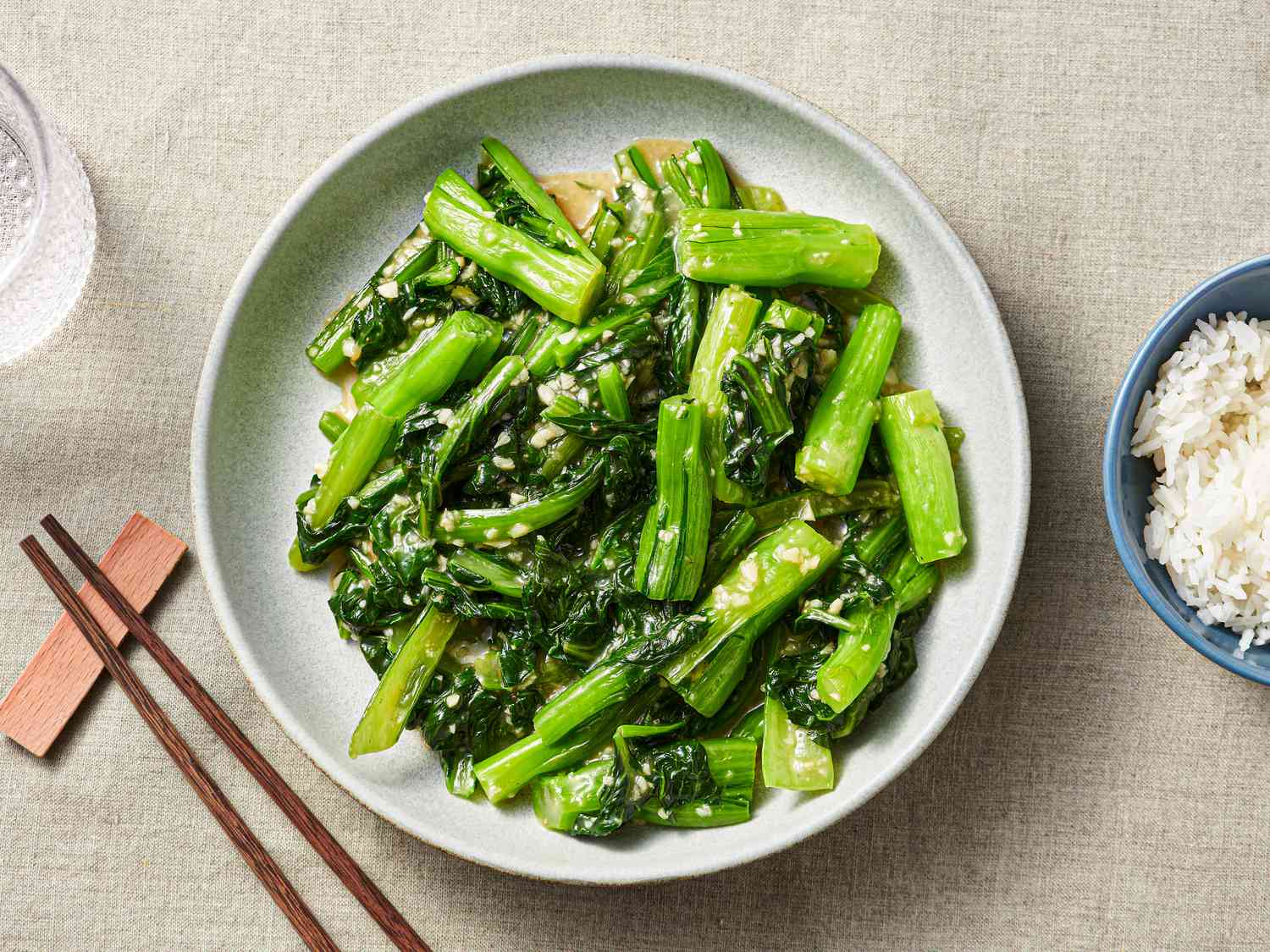 Stir-fried choy sum with minced garlic on a serving platter and a side of Jasmine rice in a small bowl