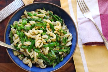 A bowl of pasta primavera with bright green vegetables.