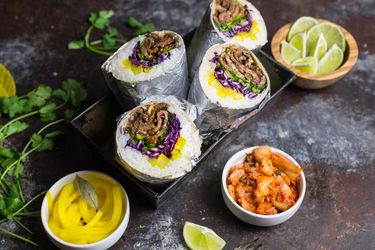 Korean beef bulgogi burritos, wrapped in foil, halved, and served as a 